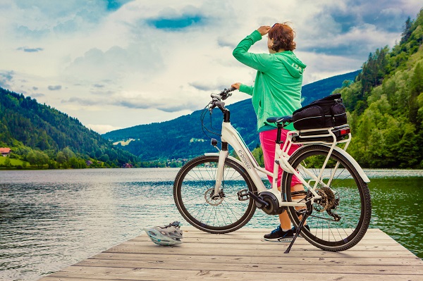 Frau mit einem E-Bike auf einem Steg am See