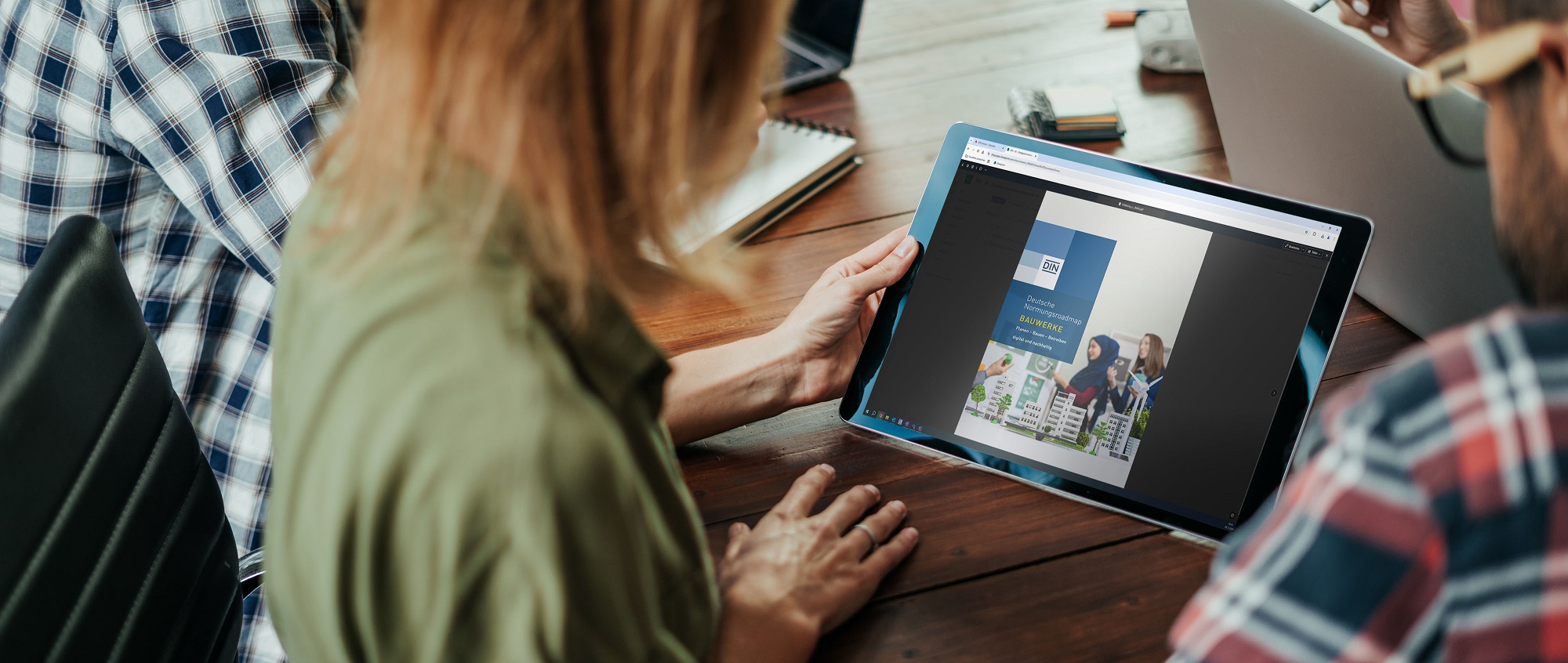 Eine Frau hält ein Touchpad mit der Normungsroadmap Bauwerke auf dem Screen