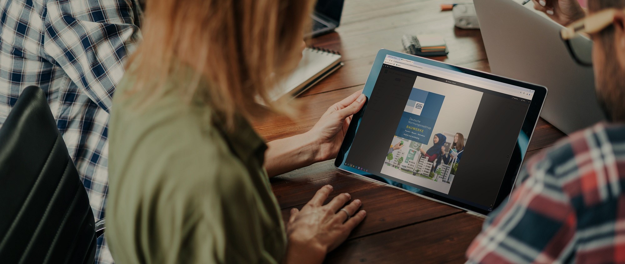 Eine Frau hält ein Touchpad mit der Normungsroadmap Bauwerke auf dem Screen