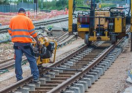 Ein Mann arbeitet mit einer Maschine an Bahngleisen