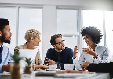 Gruppe von Personen sitzt am Tisch und diskutiert