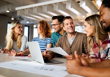 Gruppe von Personen sitzt am Tisch und arbeitet