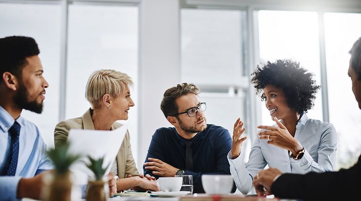 Gruppe von Personen sitzt am Tisch und diskutiert