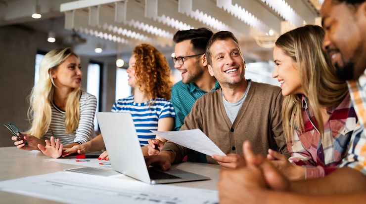 Gruppe von Personen sitzt am Tisch und arbeitet