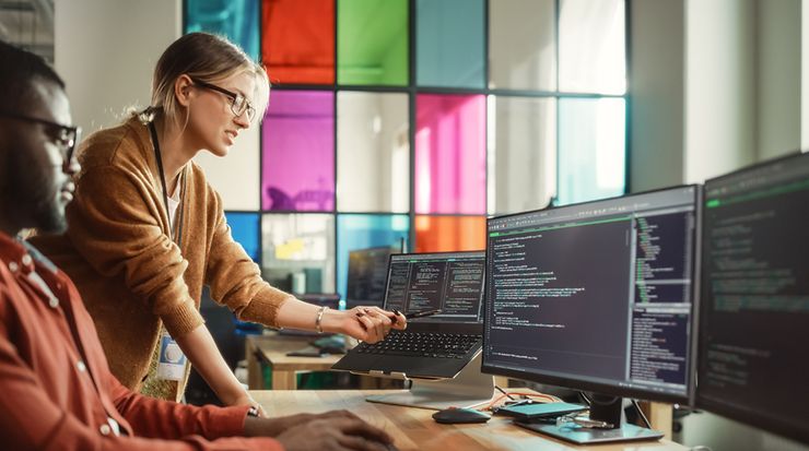 Zwei Personen schauen auf einen Bildschirm mit Code