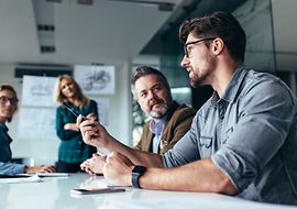 Gruppe von Personen sitzt am Tisch und diskutiert