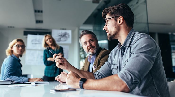 Gruppe von Personen sitzt am Tisch und diskutiert