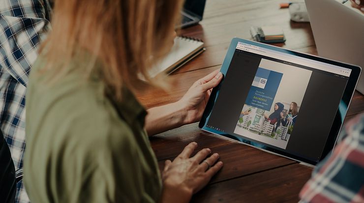 Eine Frau hält ein Touchpad mit der Normungsroadmap Bauwerke auf dem Screen