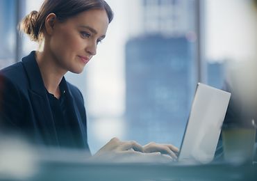 Eine Frau schaut auf ihren Laptop und tippt