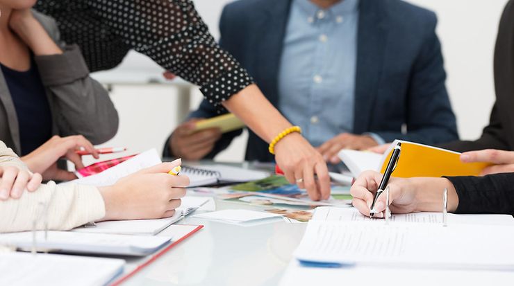 Team-Besprechung im Büro mit Stift und Papier