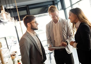 Drei Personen besprechen sich in einem Meeting-Raum